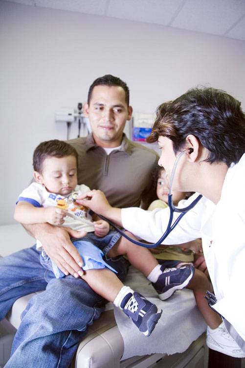 A father holds his toddler during a checkup